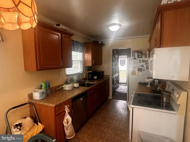 a kitchen with granite countertop a sink a stove and refrigerator