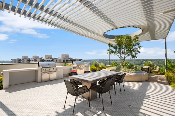 a view of a roof deck with table and chairs couches under an umbrella