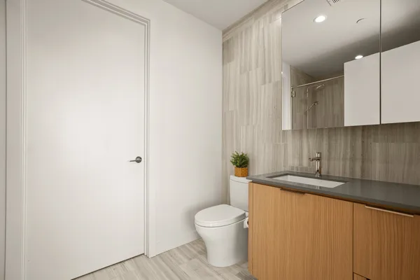 a bathroom with a granite countertop sink a toilet and a mirror