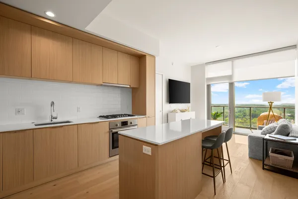 a open kitchen with stainless steel appliances granite countertop a stove top oven a sink a counter top space and living room view