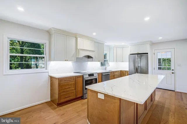 a large kitchen with stainless steel appliances granite countertop a sink dishwasher a stove and a refrigerator with wooden floor