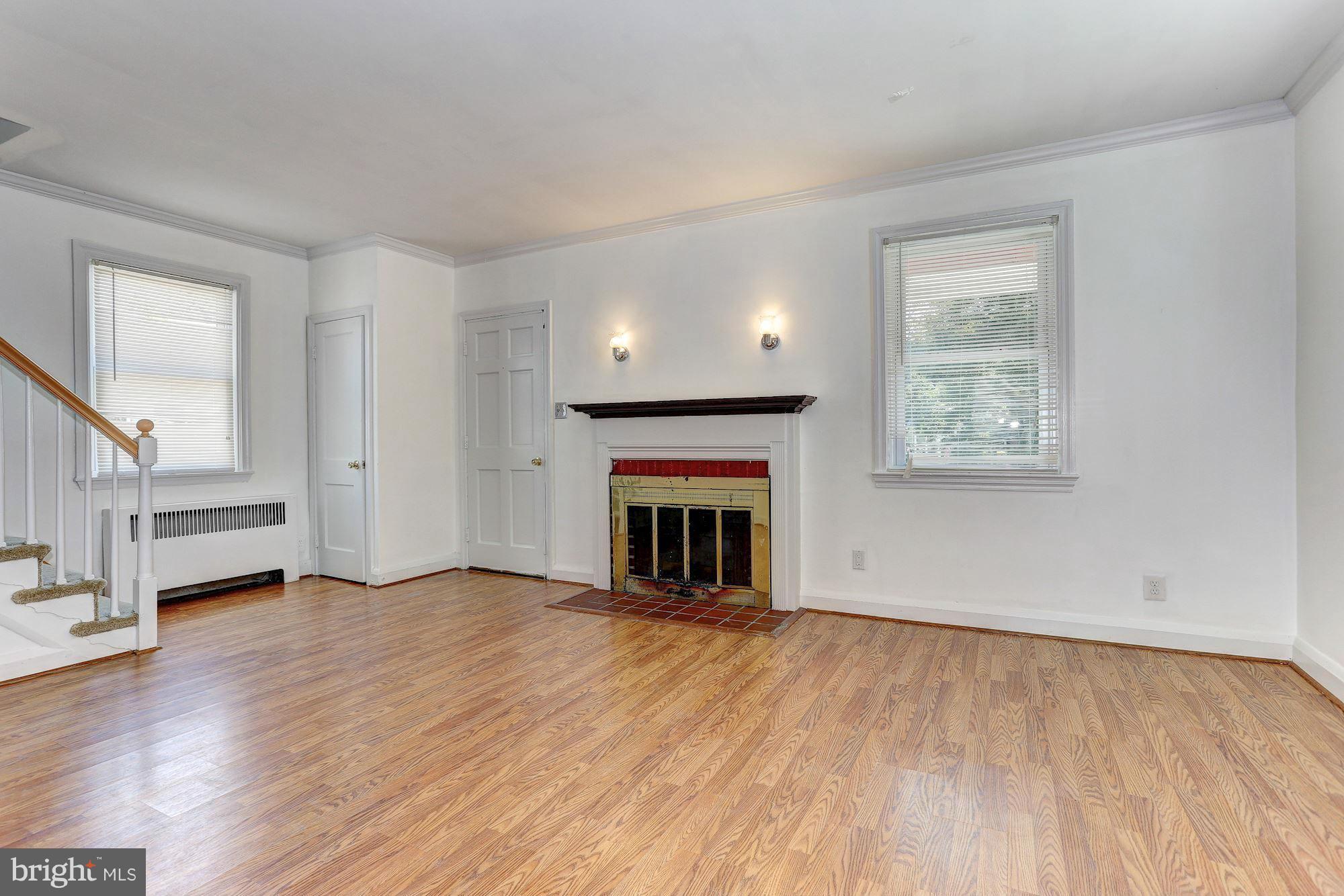 3127 Dunglow Road Baltimore, MD 21222 - Photo 2 of 14 an empty room with wooden floor fireplace and windows
