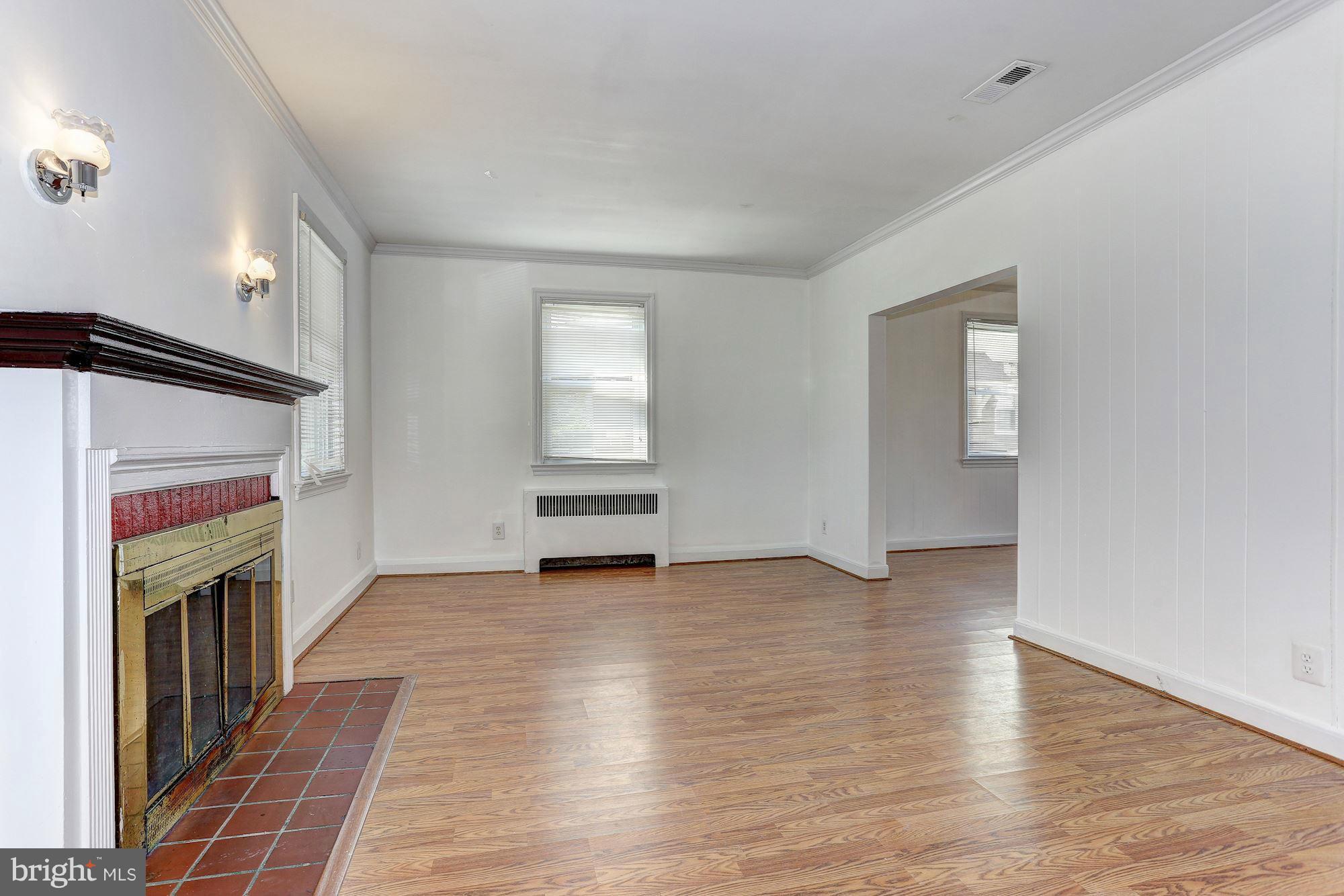 3127 Dunglow Road Baltimore, MD 21222 - Photo 3 of 14 an empty room with wooden floor fireplace and windows