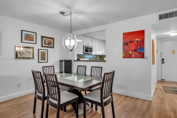 a dining room with wooden floor a chandelier a wooden table and chairs