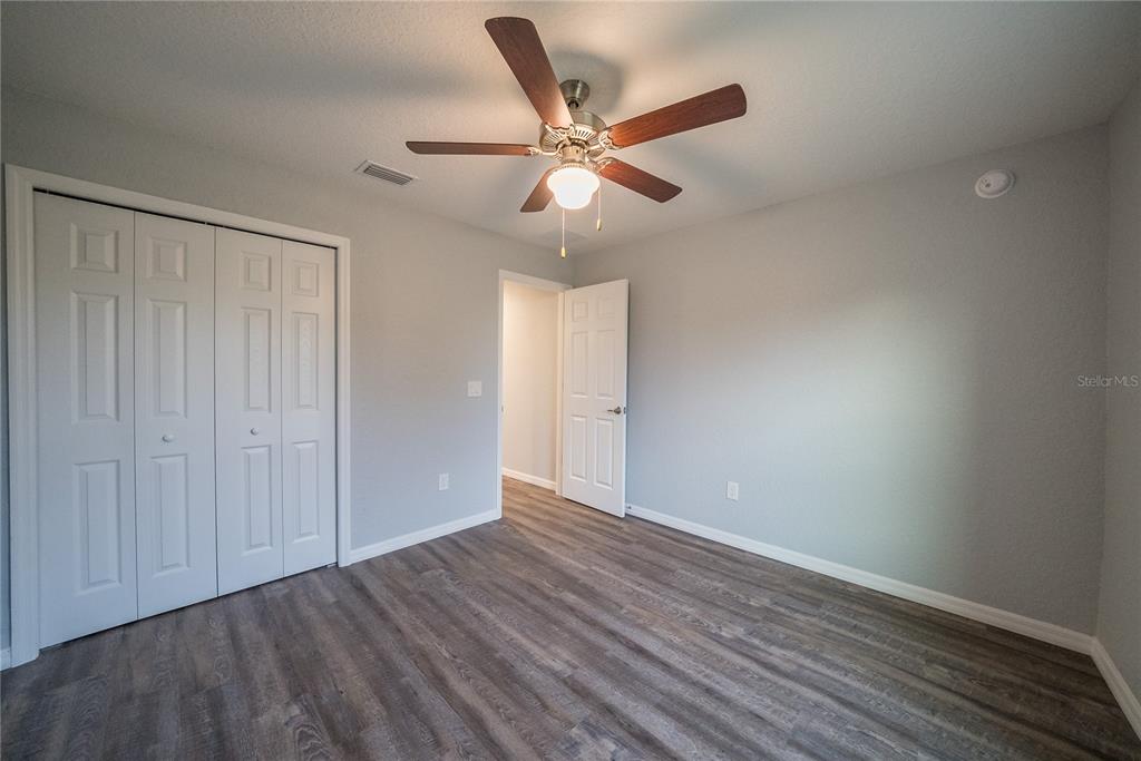 15673 Southwest 37th Circle Ocala, FL 34473 - Photo 13 of 19 a view of an empty room with wooden floor and a ceiling fan