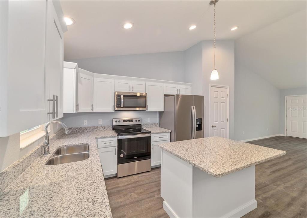 15673 Southwest 37th Circle Ocala, FL 34473 - Photo 4 of 19 a kitchen with stainless steel appliances granite countertop a sink refrigerator stove microwave and stove