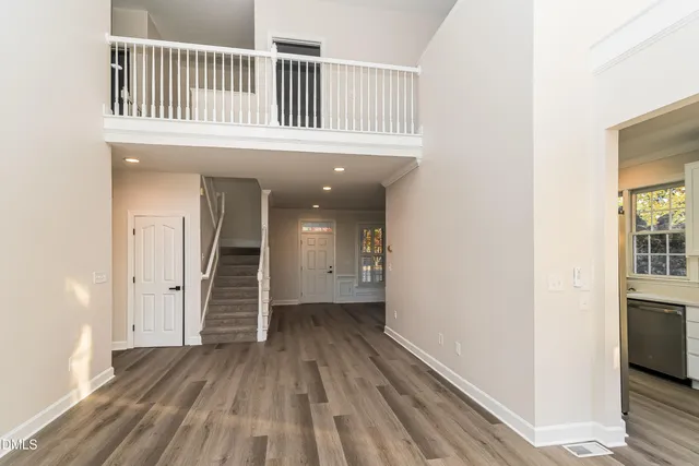 a view of a hallway with wooden floor and a bathroom