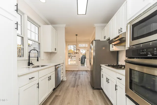 a kitchen with cabinets stainless steel appliances a sink and wooden floor