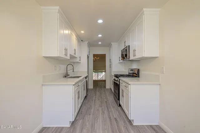 a kitchen with a sink stove top oven and white cabinets