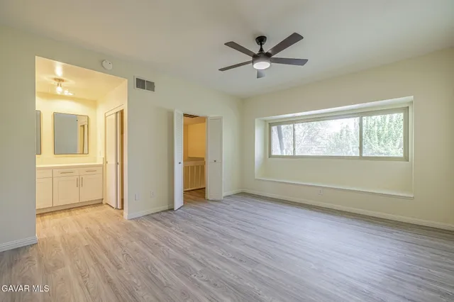 a view of empty room with wooden floor and fan