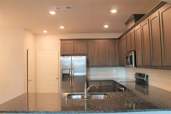 a kitchen with granite countertop a refrigerator and a sink