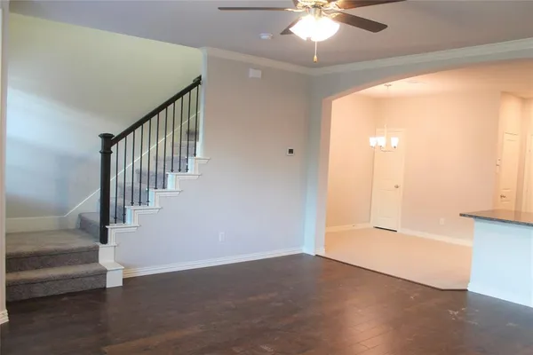 a view of an empty room with wooden floor and a chandelier