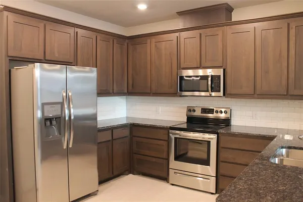 a kitchen with granite countertop a refrigerator stove and microwave