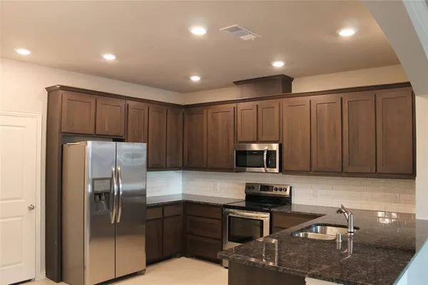 a kitchen with granite countertop stainless steel appliances and wooden cabinets