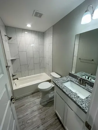a bathroom with a granite countertop sink mirror vanity and toilet