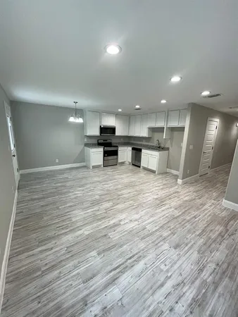 a view of a kitchen with kitchen island wooden floors wooden cabinets and stainless steel appliances