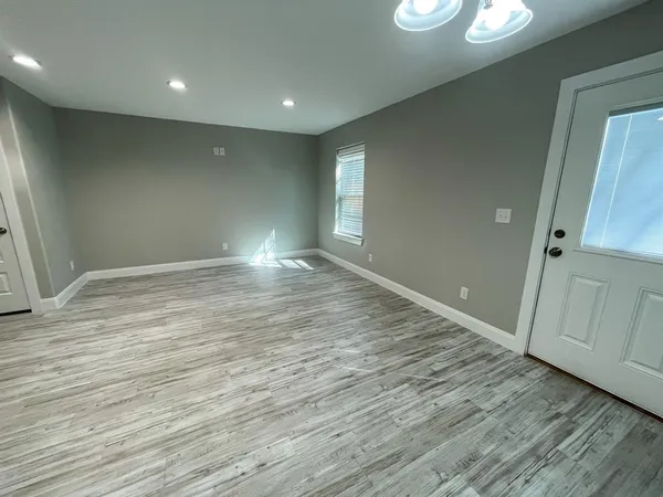 an empty room with wooden floor and entrance