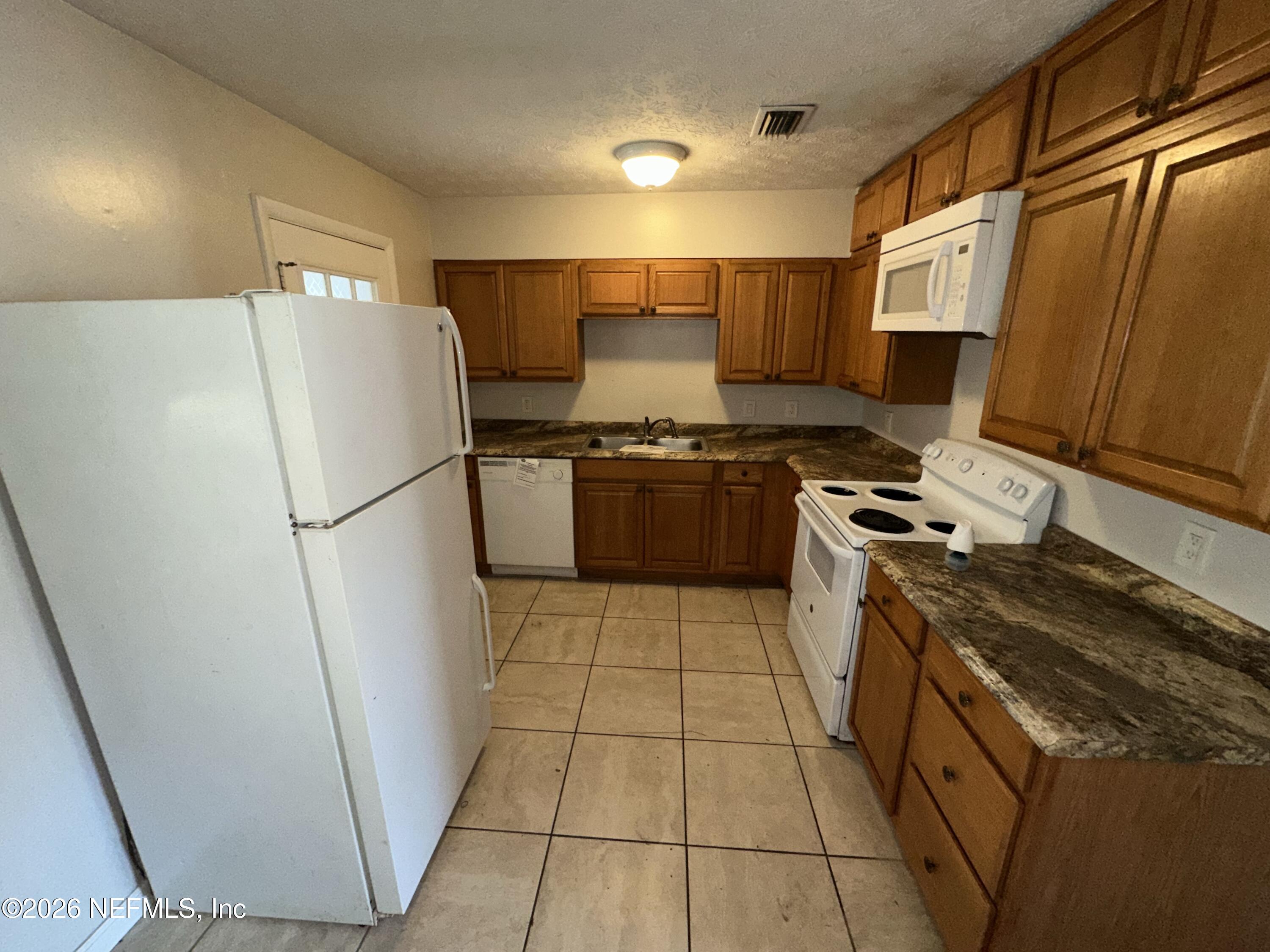 4435 Rainer Road Jacksonville, FL 32210 - Photo 6 of 14 a kitchen with stainless steel appliances granite countertop a refrigerator a stove a sink and a microwave