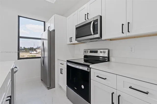 a kitchen with white cabinets and black appliances