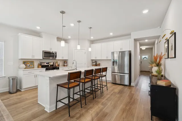a kitchen with stainless steel appliances a stove a sink and white cabinets