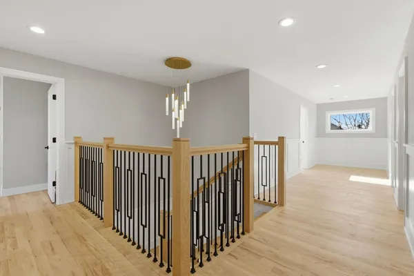 a view of a hallway with wooden floor and chandelier