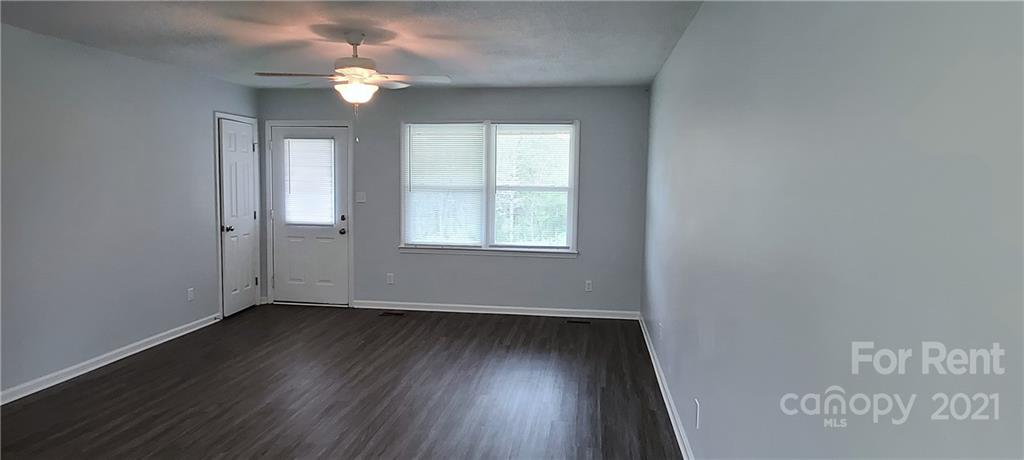 3560 Boggs Road Claremont, NC 28610 - Photo 4 of 15 an empty room with wooden floor chandelier fan and windows