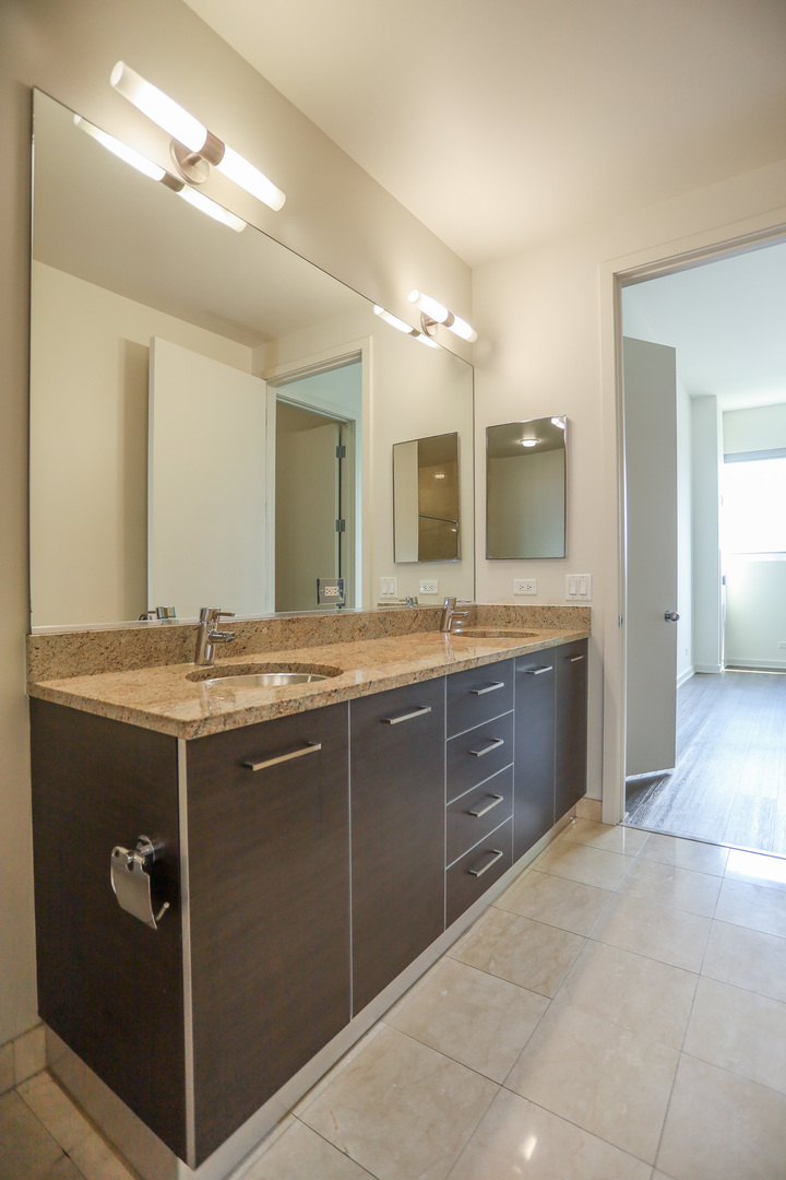 910 West Huron Street, Unit 1310 Chicago, IL 60642 - Photo 14 of 25 a spacious bathroom with a granite countertop sink a mirror and a