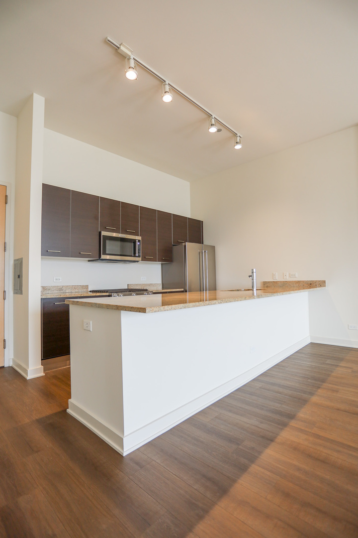 910 West Huron Street, Unit 1310 Chicago, IL 60642 - Photo 2 of 25 a view with kitchen island a sink wooden floor and a refrigerator
