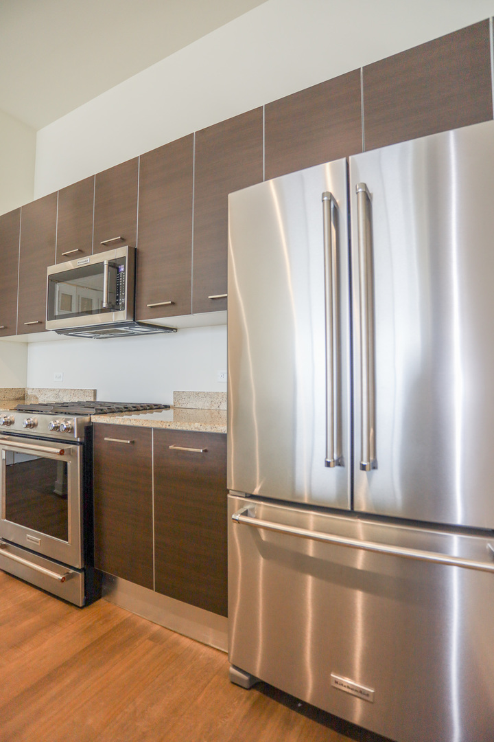 910 West Huron Street, Unit 1310 Chicago, IL 60642 - Photo 7 of 25 a view of a kitchen with a refrigerator cabinets and a wooden floor