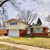 a front view of a house with a garden and tree