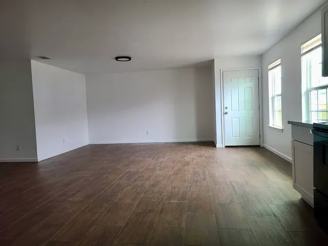 a view of an empty room with a window and wooden floor