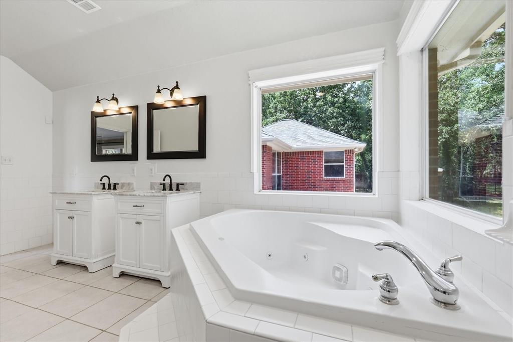 289 County Road 1170 Decatur, TX 76234 - Photo 21 of 40 Primary ensuite with double vanities with granite countertops, Oversized corner tub and beautiful windows looking onto the heavily treed backyard.