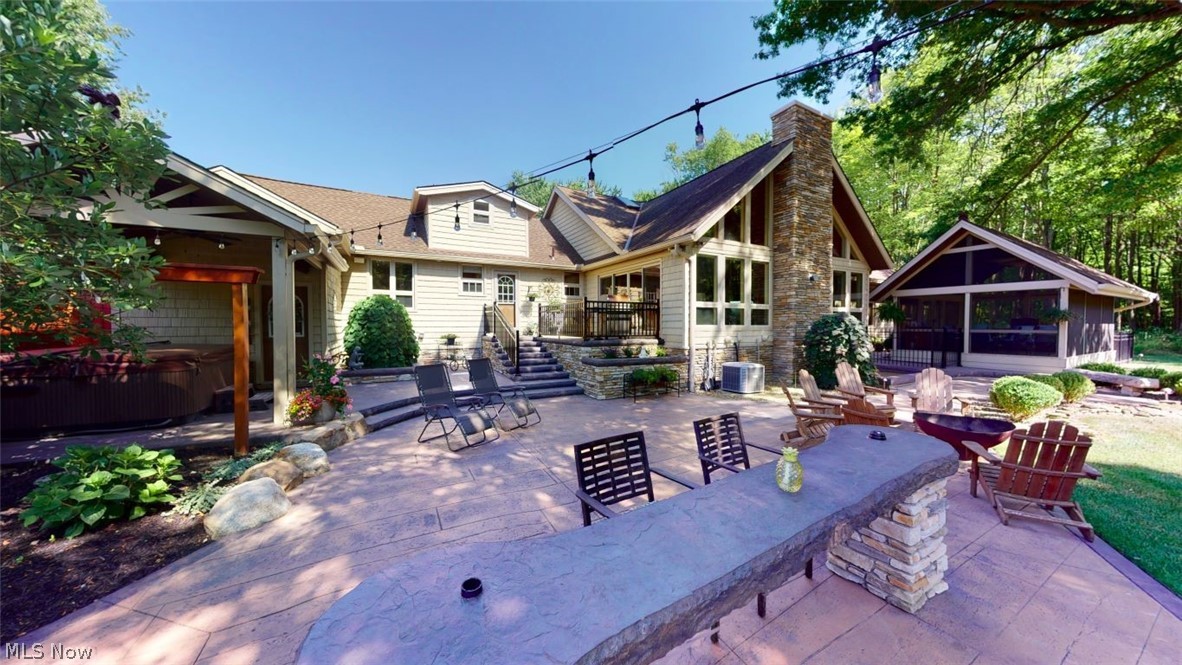 6556 Stone Road Hudson, OH 44236 - Photo 26 of 35 Back view of home featuring a massive stamped concrete patio, hot tub, bar, firepit and large screened in porch.