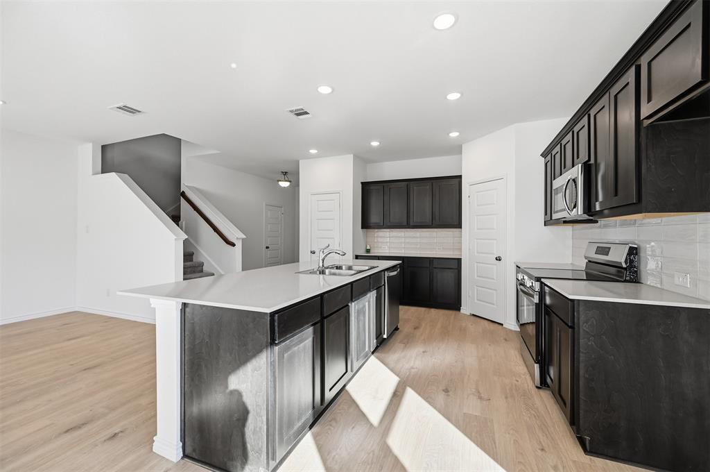 400 Wrangler Lane, Unit 400 Denton, TX 76209 - Photo 2 of 18 a kitchen with stainless steel appliances kitchen island granite countertop a stove a sink and a refrigerator