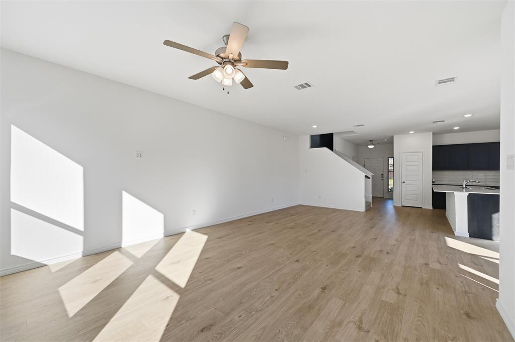 400 Wrangler Lane, Unit 400 Denton, TX 76209 - Photo 6 of 18 a view of an empty room with wooden floor and a kitchen