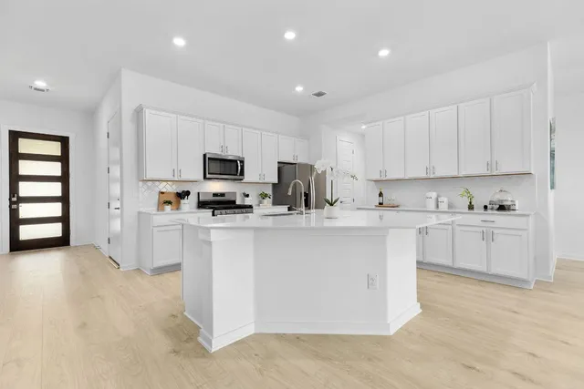 a kitchen with granite countertop white cabinets and stainless steel appliances