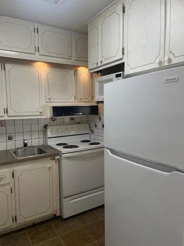 a kitchen with white cabinets and white appliances