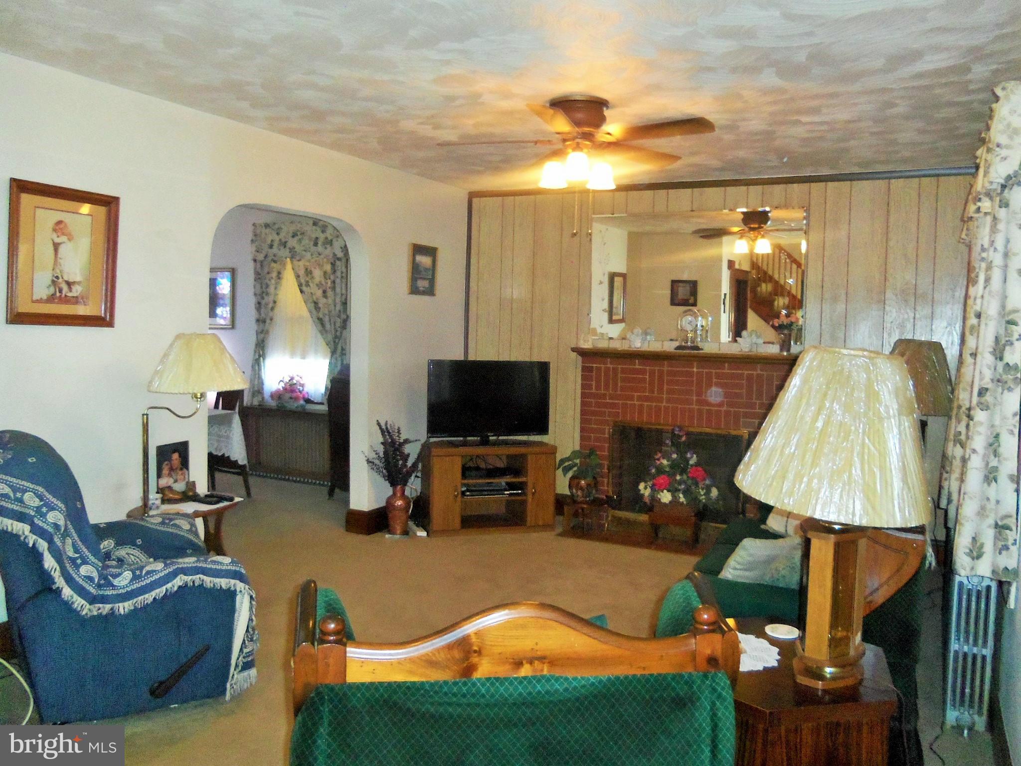 5574 Ashbourne Road Baltimore, MD 21227 - Photo 6 of 29 a living room with furniture a lamp a fireplace and a flat screen tv