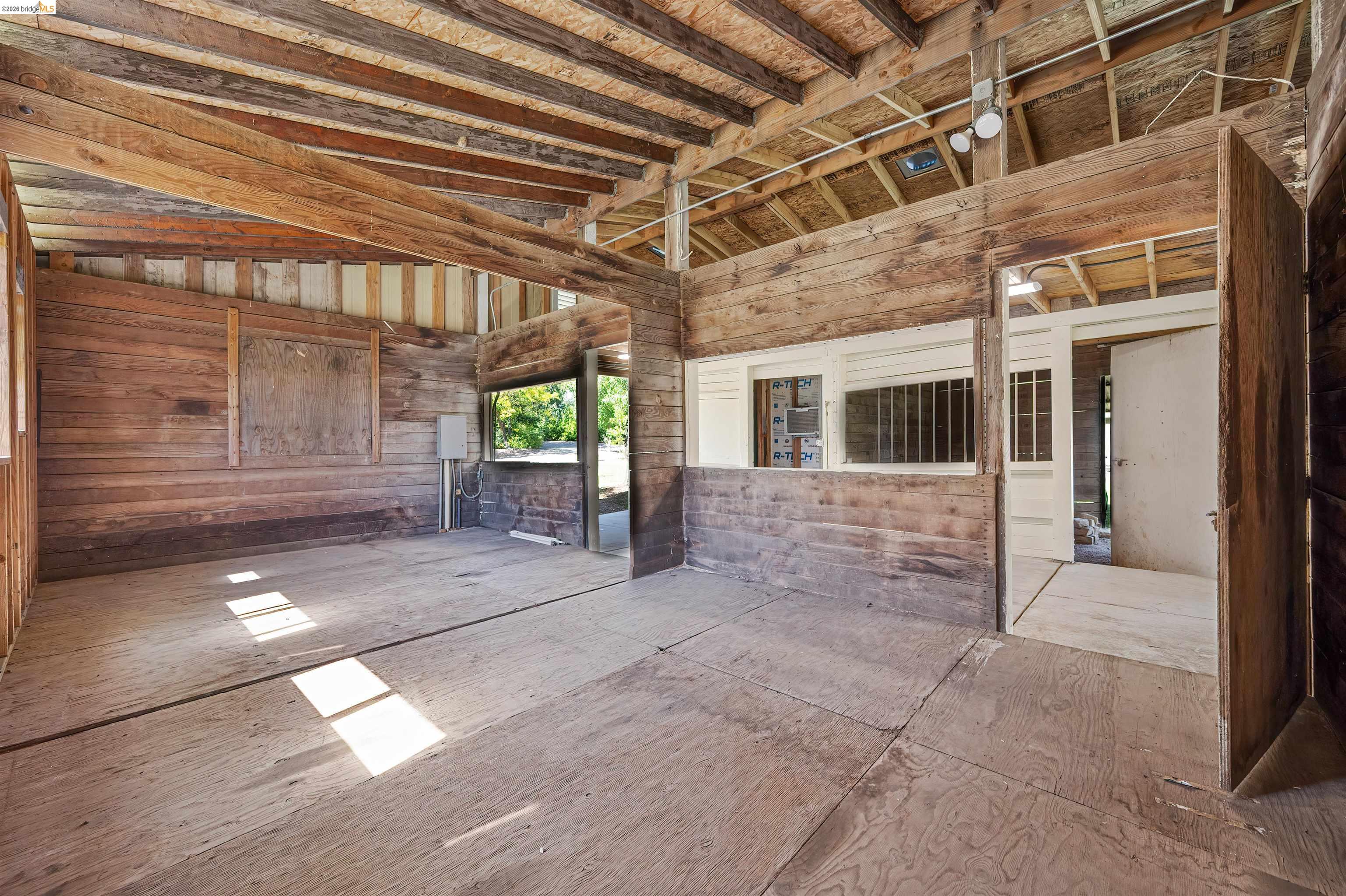 10474 Sheldon Road Elk Grove, CA 95624 - Photo 58 of 83 Spacious interior featuring exposed wood beams, wood-finish wall panels, and an open doorway leading to another area