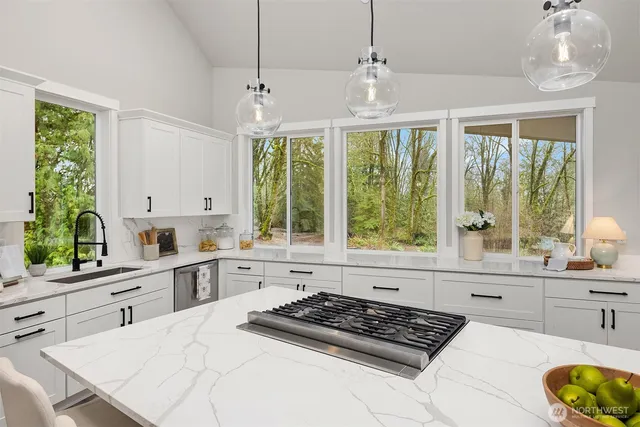 a kitchen with stainless steel appliances kitchen island granite countertop a stove a sink dishwasher and white cabinets with wooden floor