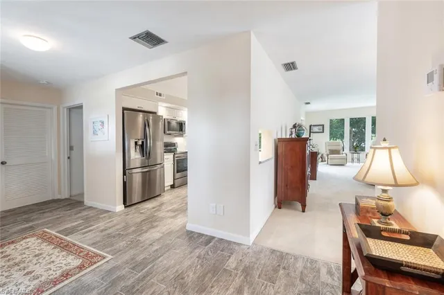 a view of a kitchen with refrigerator and wooden floor