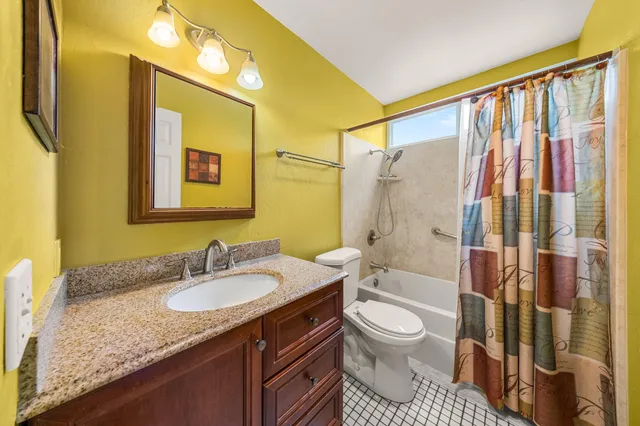a bathroom with a granite countertop sink toilet and shower