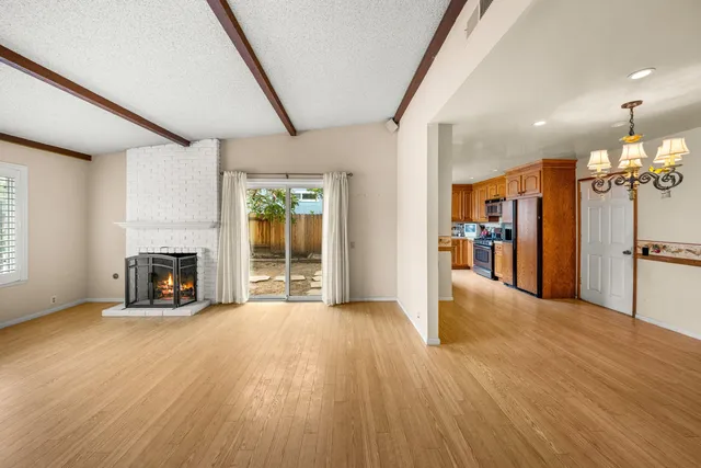 a view of a livingroom with a fireplace a ceiling fan and windows