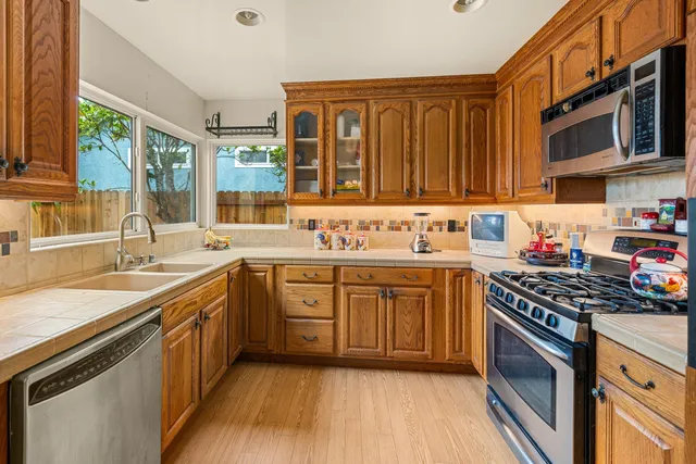 a kitchen with stainless steel appliances granite countertop a stove a sink dishwasher and a microwave oven with wooden cabinets