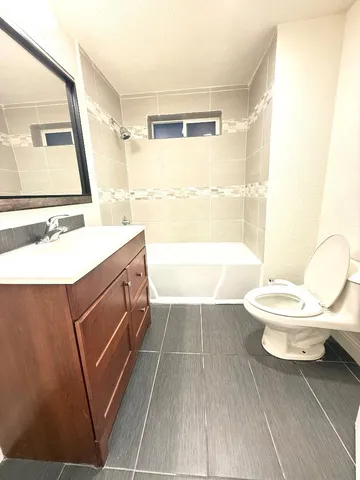 a bathroom with a sink a toilet a window and vanity
