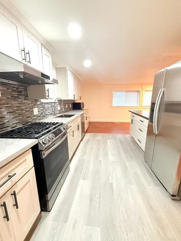 a kitchen with granite countertop a sink stove and cabinets