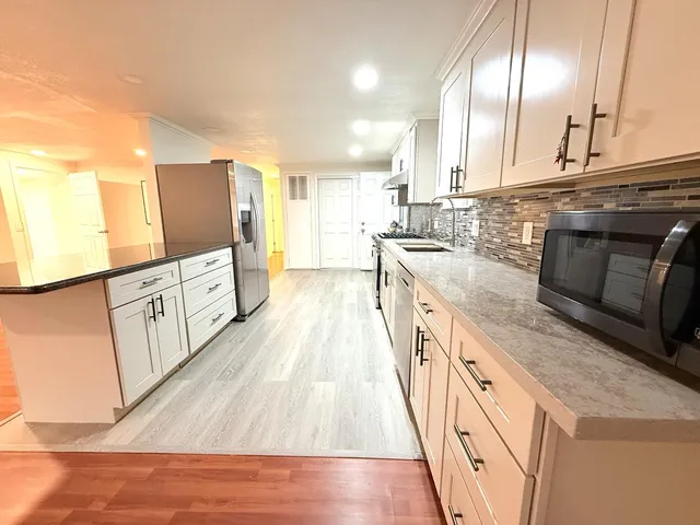 a large kitchen with stainless steel appliances granite countertop a lot of counter space and wooden floors