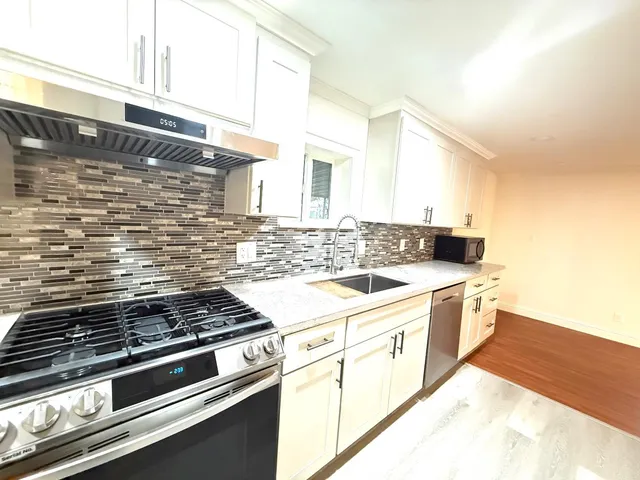 a kitchen with stainless steel appliances granite countertop a stove and white cabinets