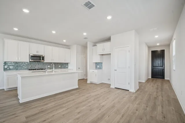 a large kitchen with stainless steel appliances granite countertop a stove a sink and white cabinets