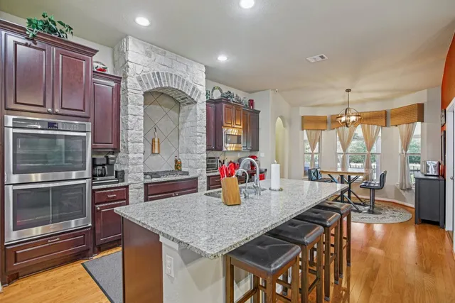 a kitchen with stainless steel appliances granite countertop a stove top oven a sink and cabinets